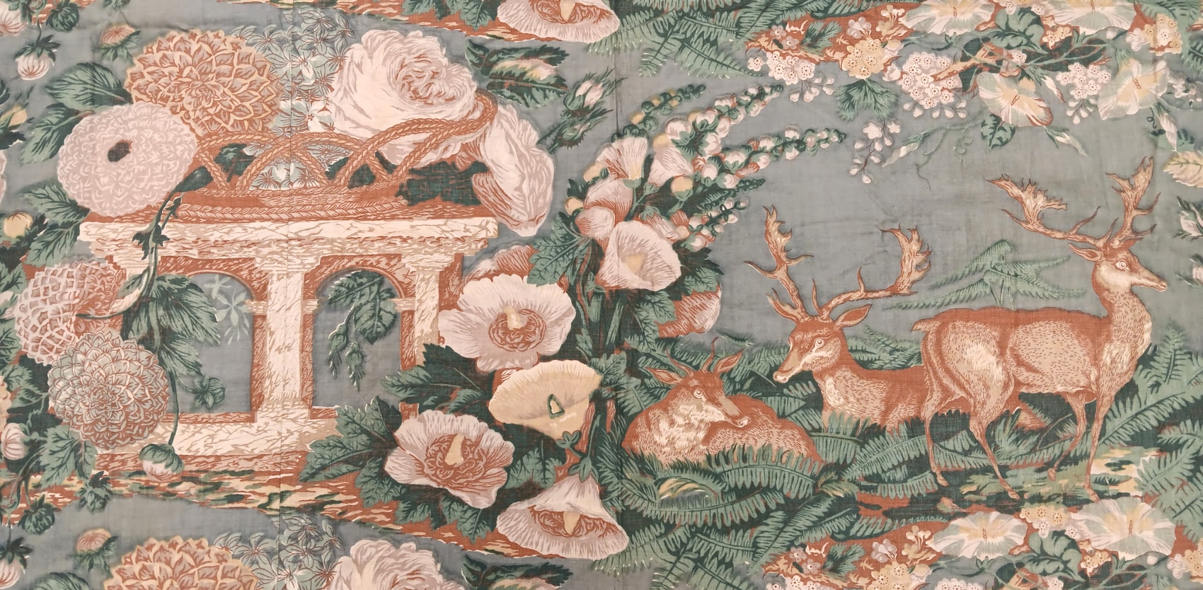 Textile pattern depicting deer resting amoung various leaves and flowers